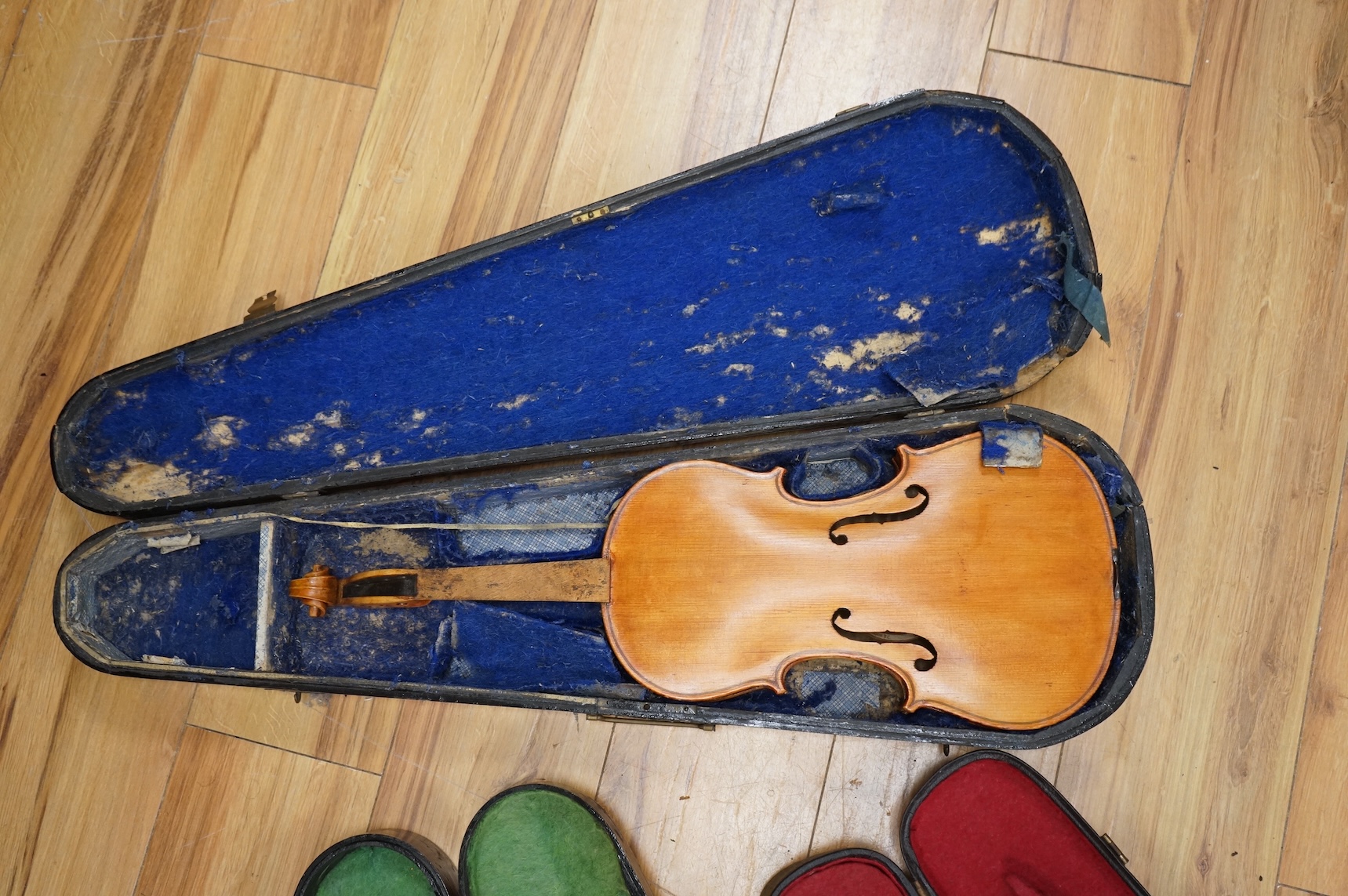 Three violins; a late 19th century German Stradivarius pattern violin, without label, a handmade violin (a.f.), with sound post crack, broken and repaired scroll, etc. and a Maidstone violin body, varnish stripped from t